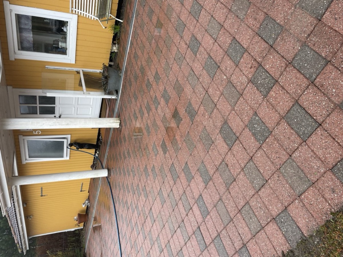 Efter: Gårdsplads af røde og grå belægningssten foran et gult hus
