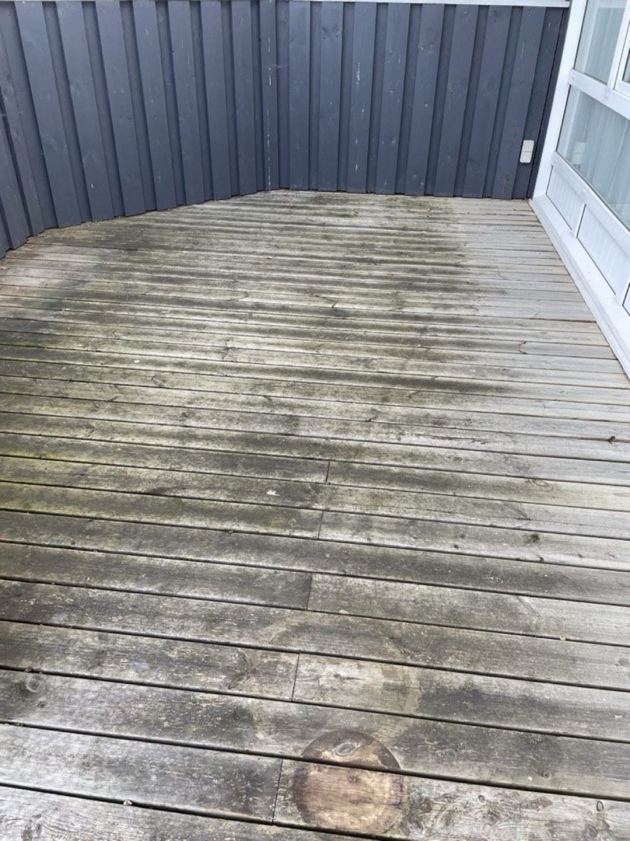 Før: Hjørneterrasse af træ ved et sort sommerhus