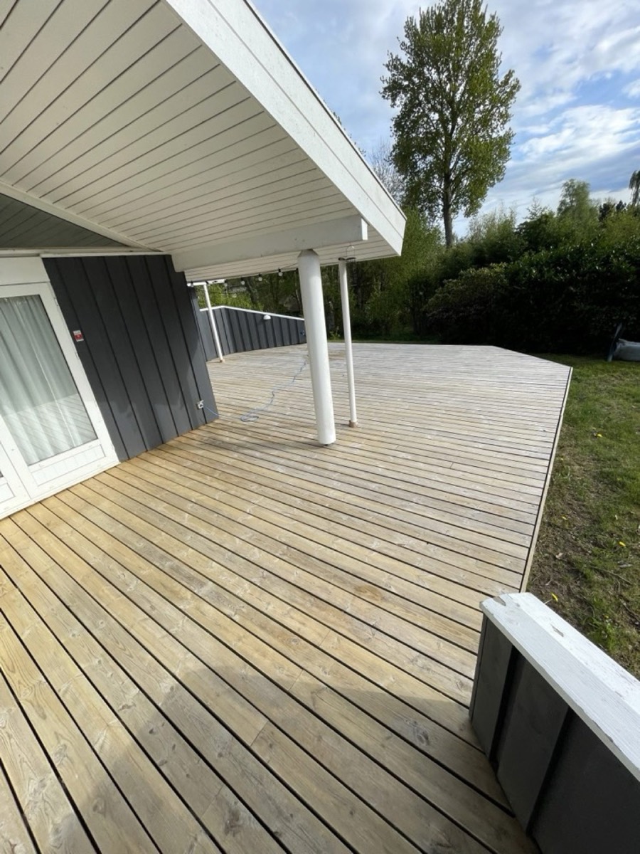Efter: Stor træterrasse under overdækning ved et sort træhus