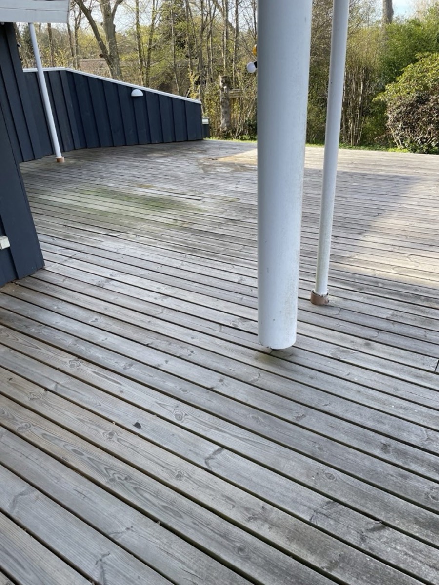 Før: Stor træterrasse under overdækning ved et sort træhus
