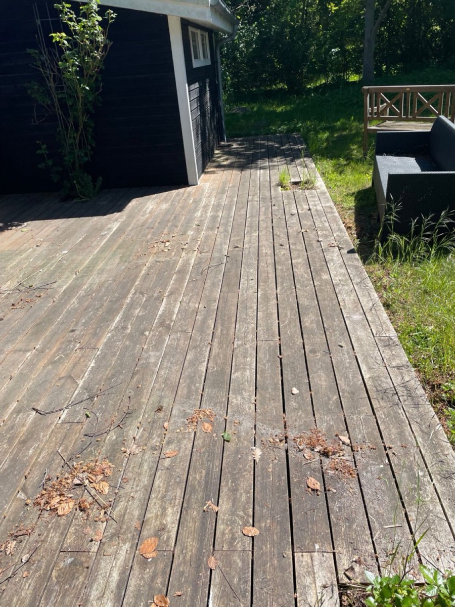 Før: Træterrasse med diagonalt mønster ved et sort træhus i skoven