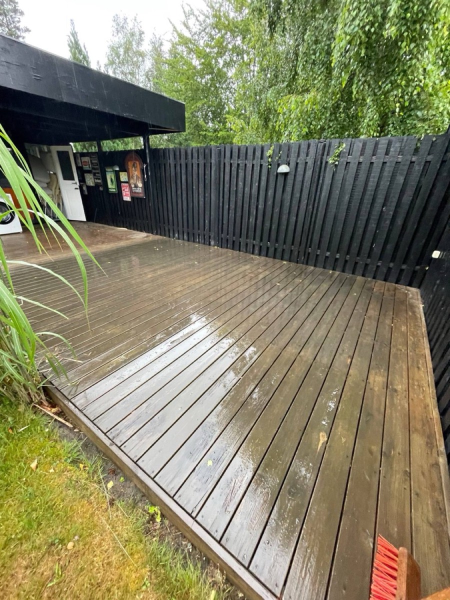 Før: Træterrasse inde bag et sort plankeværk