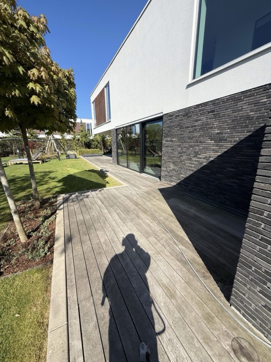 Før: Træterrasse langs et moderne hus med mørk teglsokkel