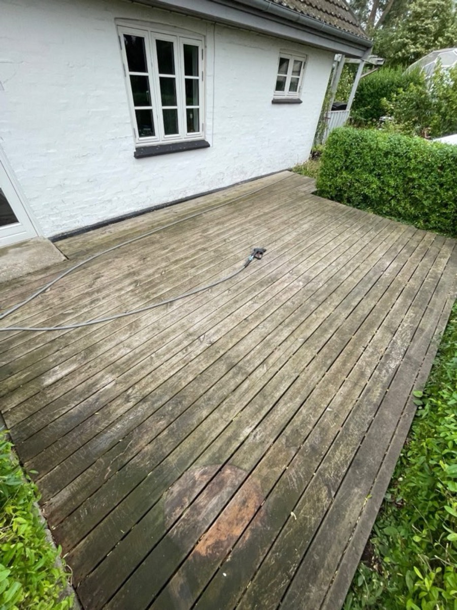 Før: Træterrasse ved et hvidt hus med hæk