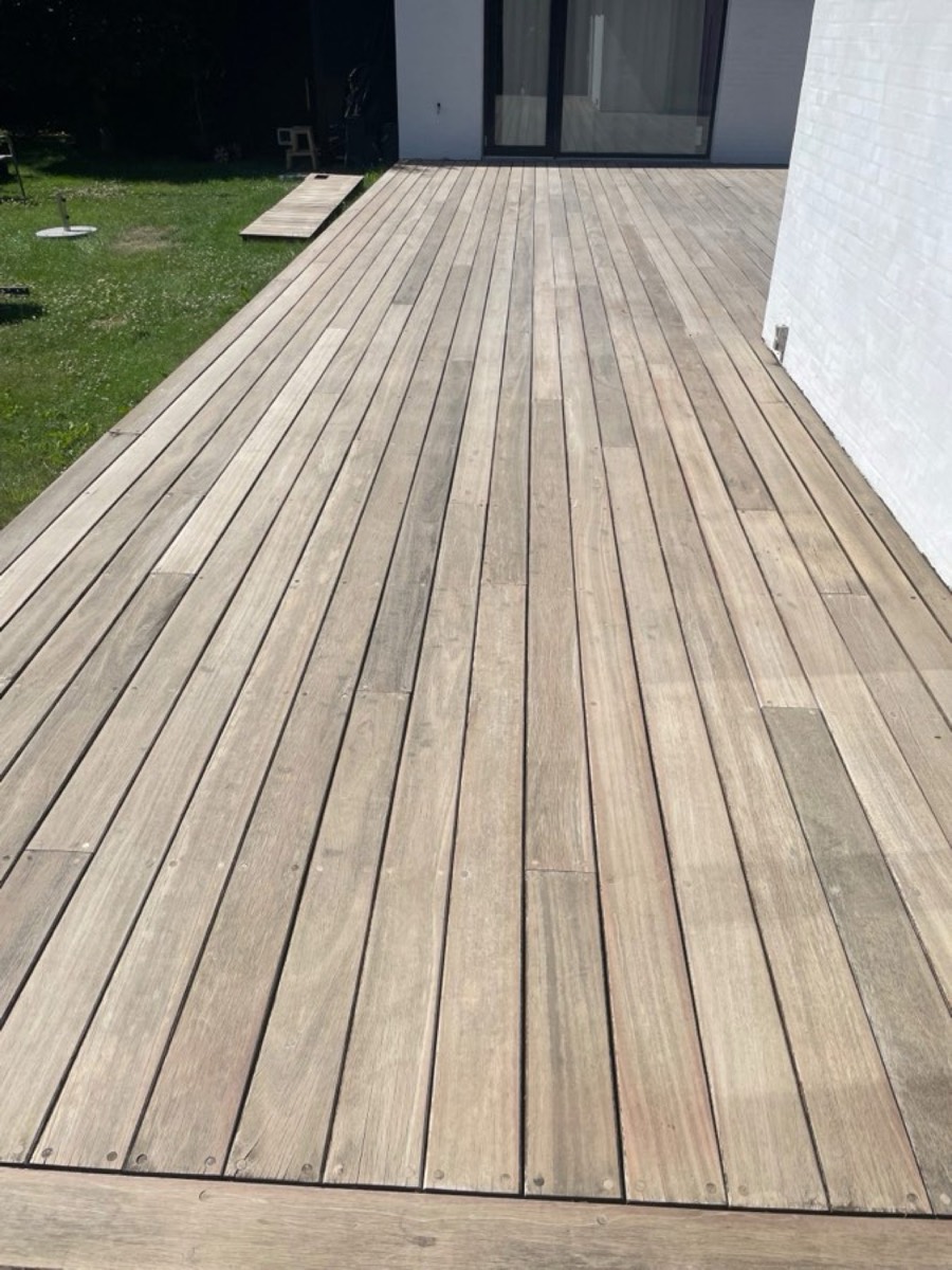 Efter: Lang terrasse af hårdttræ langs et hvidt hus