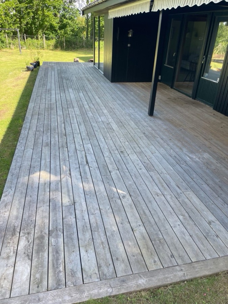 Før: Træterrasse under overdækning ved et sort sommerhus