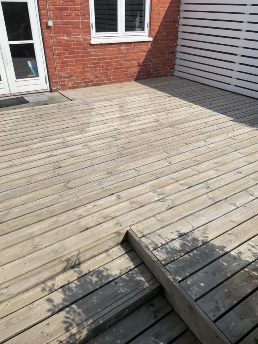 Efter: Træterrasse med hvidt plankeværk ved et rødt murstenshus