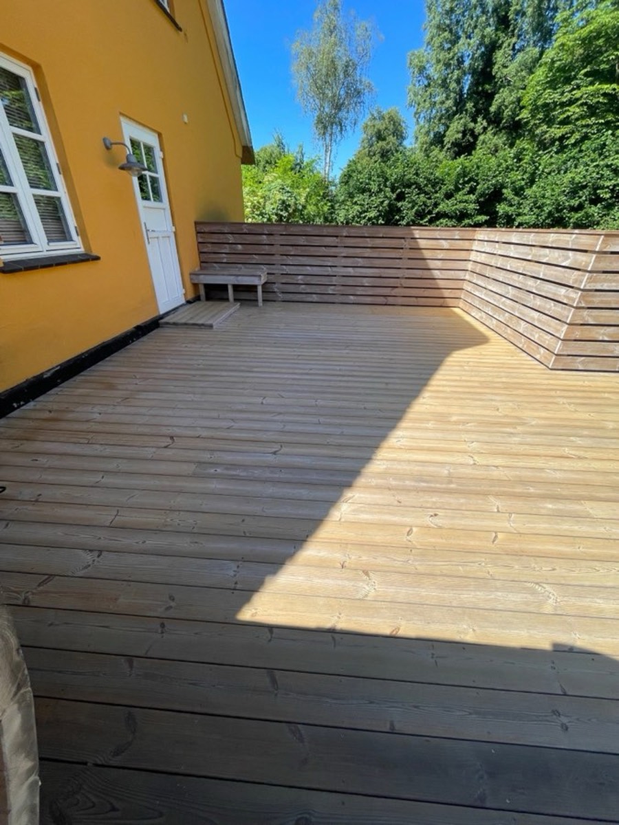 Efter: Træterrasse med indbygget bænk ved et gult hus